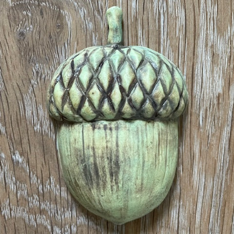 Ceramic acorn on a wooden surface