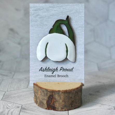 Enamel brooch on a wooden stand with a gray geometric background