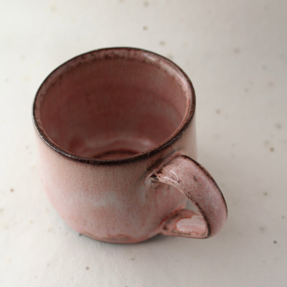 Pink ceramic mug on a light speckled surface