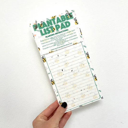 Hand holding a plantable list pad with a white background