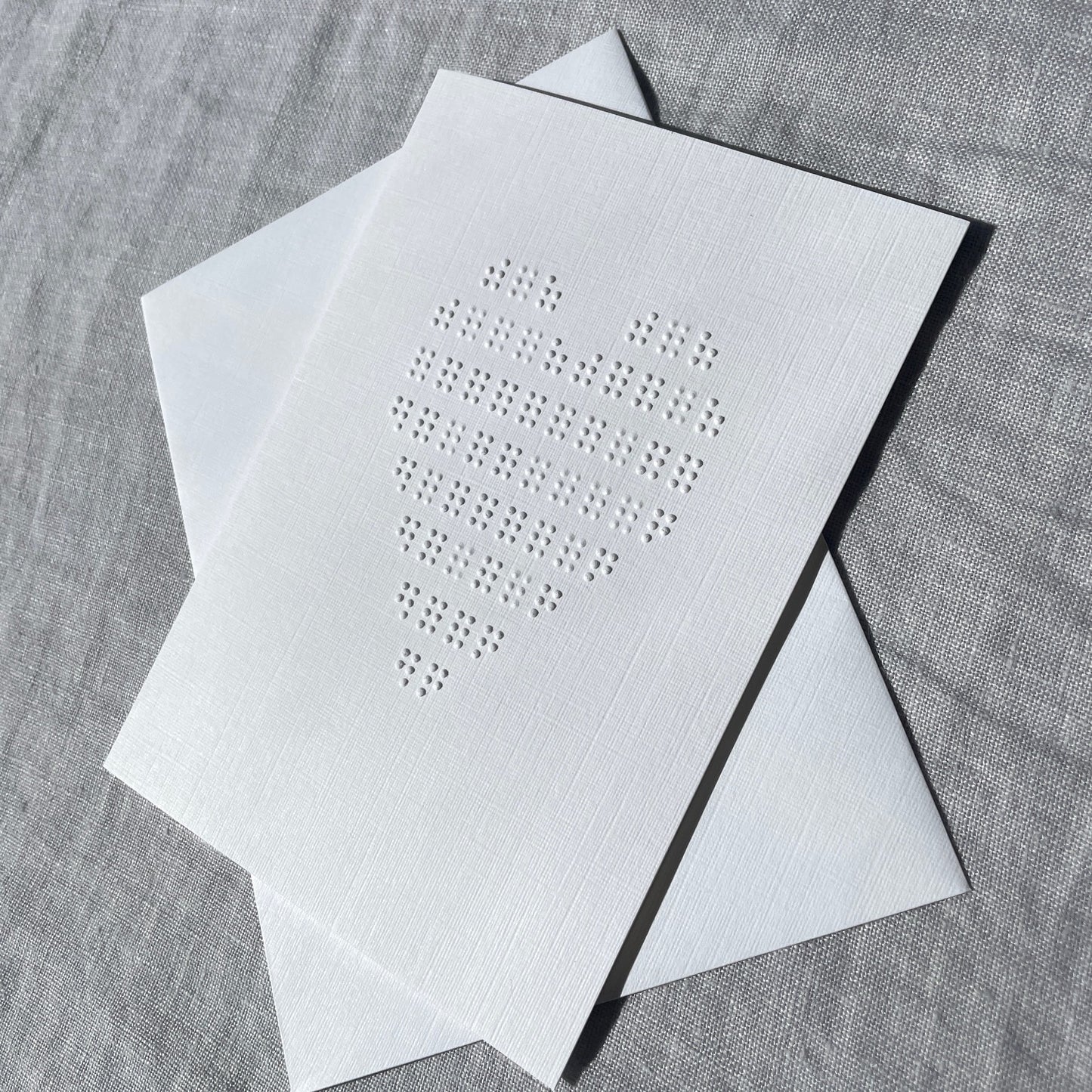 White card with embossed heart on a white textured surface.