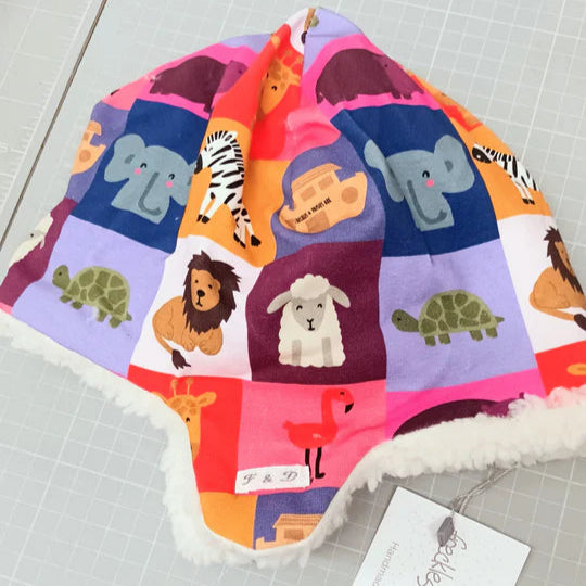Colorful baby hat with animal patterns on a checkered background