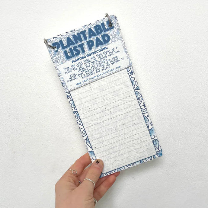 Hand holding a plantable list pad with a white background