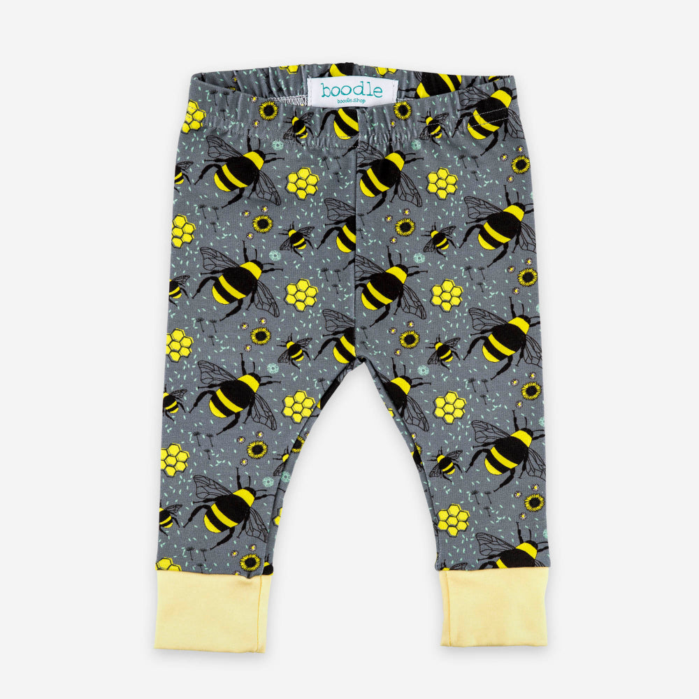 Gray patterned baby leggings with a yellow and black bumblebee print, featuring light yellow cuffed hems and a visible 'boodie' brand label at the waistband.