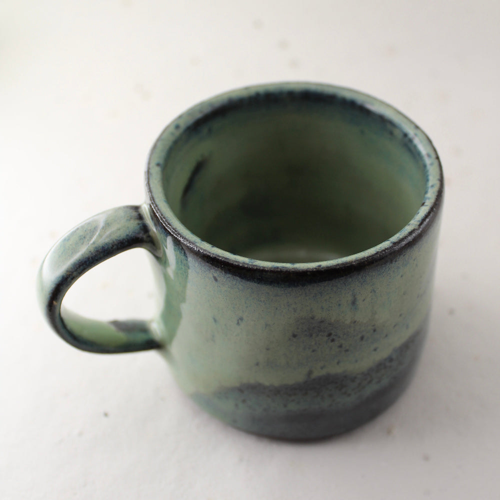Dark green ceramic mug with speckled texture on a white background